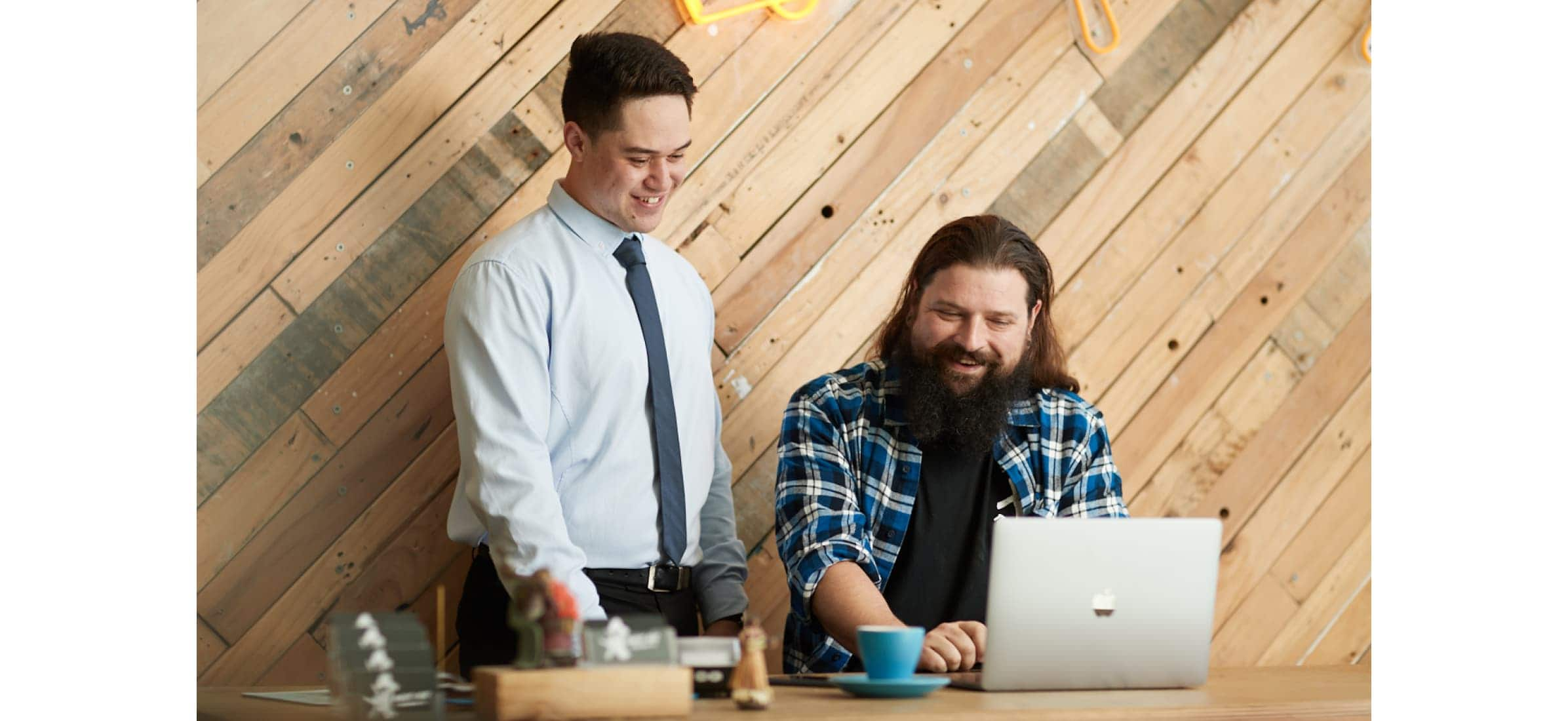 Owner of Sweet Axe Throwing, Lloyd Bombell, talking over a computer with their accountant, Devoe Rangi.